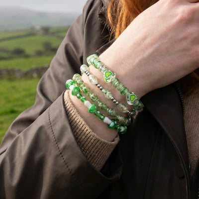 NOGU Emerald Isle collection bracelets stacked in green, white, and clear glass beads with silver accents and heart details.