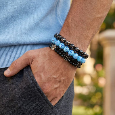 NOGU Made to Pair Blue Seaspray bracelet stack with cool blue speckled glass beads, black beads, and smiley charms.