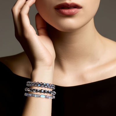 NOGU October’s Color Palette stack of smoky grey, silver, and black beaded bracelets styled on a wrist with a black top.