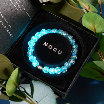 NOGU Firework Neon bracelet with glowing electric-blue beads and iridescent flecks, displayed in a black gift box.