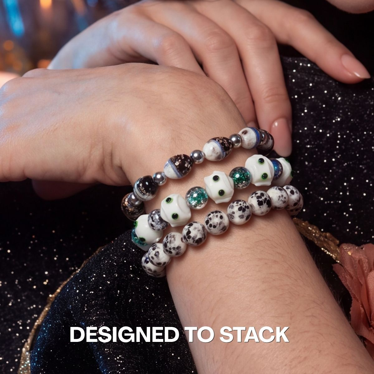 Stacked beaded bracelets with white cat charms, green glitter beads, and black-and-white speckled stones.