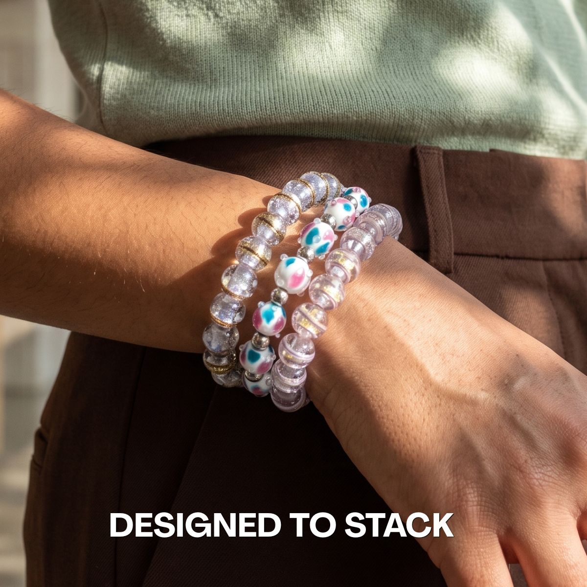 Stacked NOGU beaded bracelets with clear lavender glass beads and white beads accented in teal and pink.