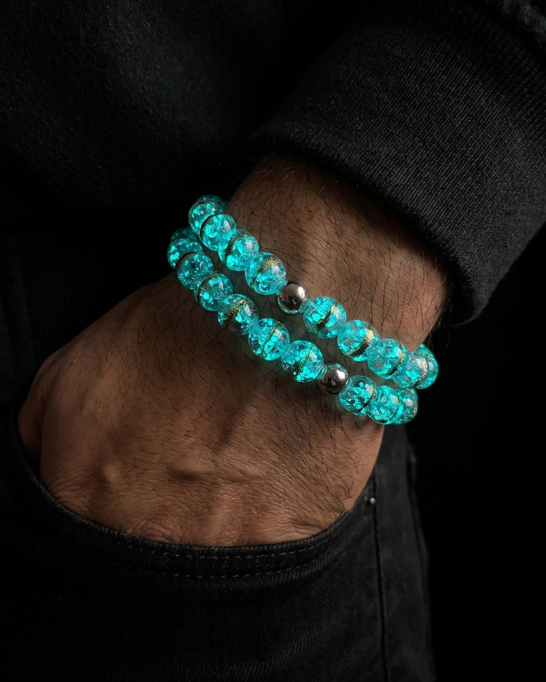Stacked turquoise crackle-glass bead bracelets with polished silver-tone accent beads, worn on a wrist.
