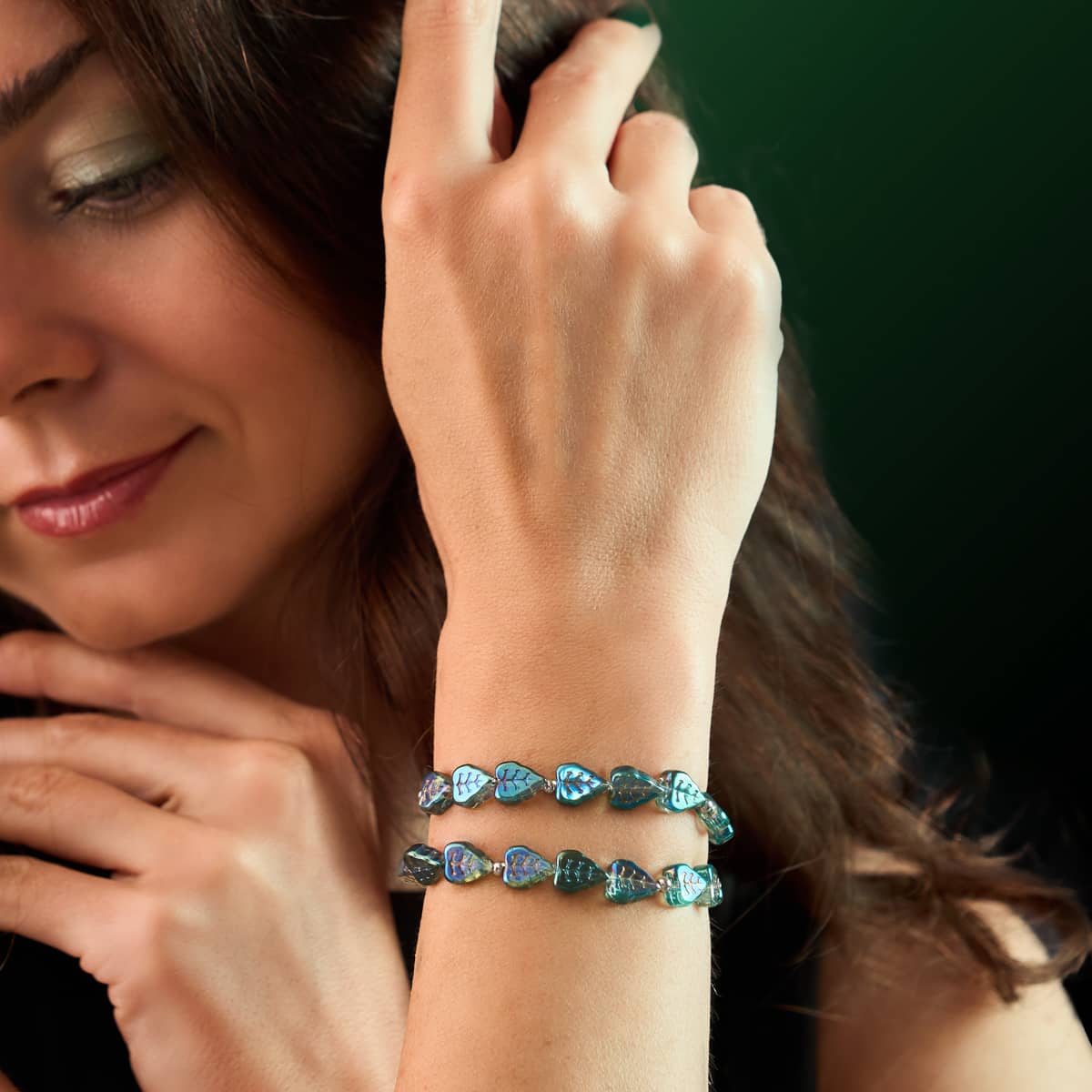 Poison Ivy leaf wrap bracelet with iridescent blue leaves and clear stretch cord worn doubled on wrist by NOGU