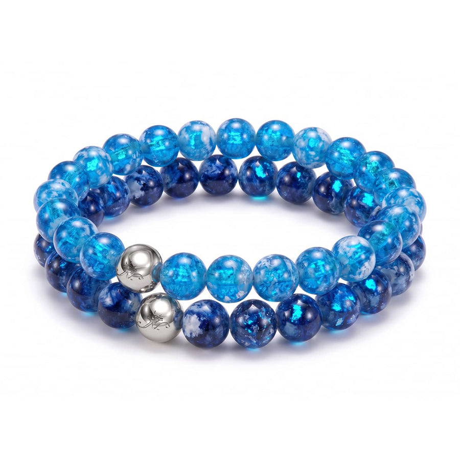 Set of two blue firefly glass porcelain bead bracelets with polished stainless steel logo beads on clear elastic cords.