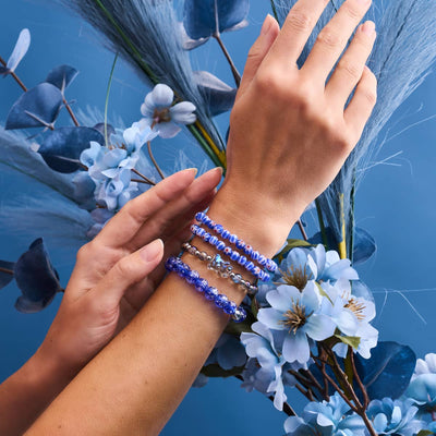 Lapis Lazuli Firefly Glass Bracelet with glowing blue beads and .925 sterling silver clasp worn with other colorful bracelets by NOGU