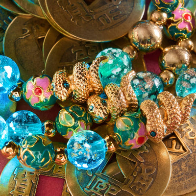 Sea Dragon bracelet with teal firefly glass, enamel lotus beads, and gold serpent charm on Chinese coins by NOGU