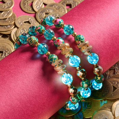 Sea Dragon bracelet with teal firefly glass and enamel lotus beads, gold serpent charm, and stainless steel on red with Chinese coins by NOGU