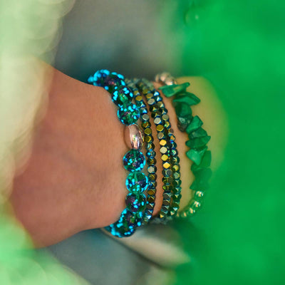 Blue Shamrock Firefly Glass bracelet with glowing beads paired with multicolor faceted and malachite stone bracelets on wrist by NOGU