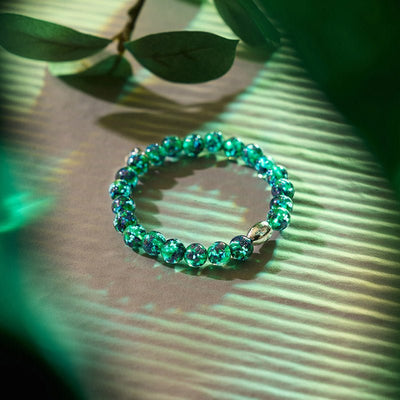 Blue Shamrock bracelet with turquoise speckled beads and white gold accent bead on green striped surface by NOGU