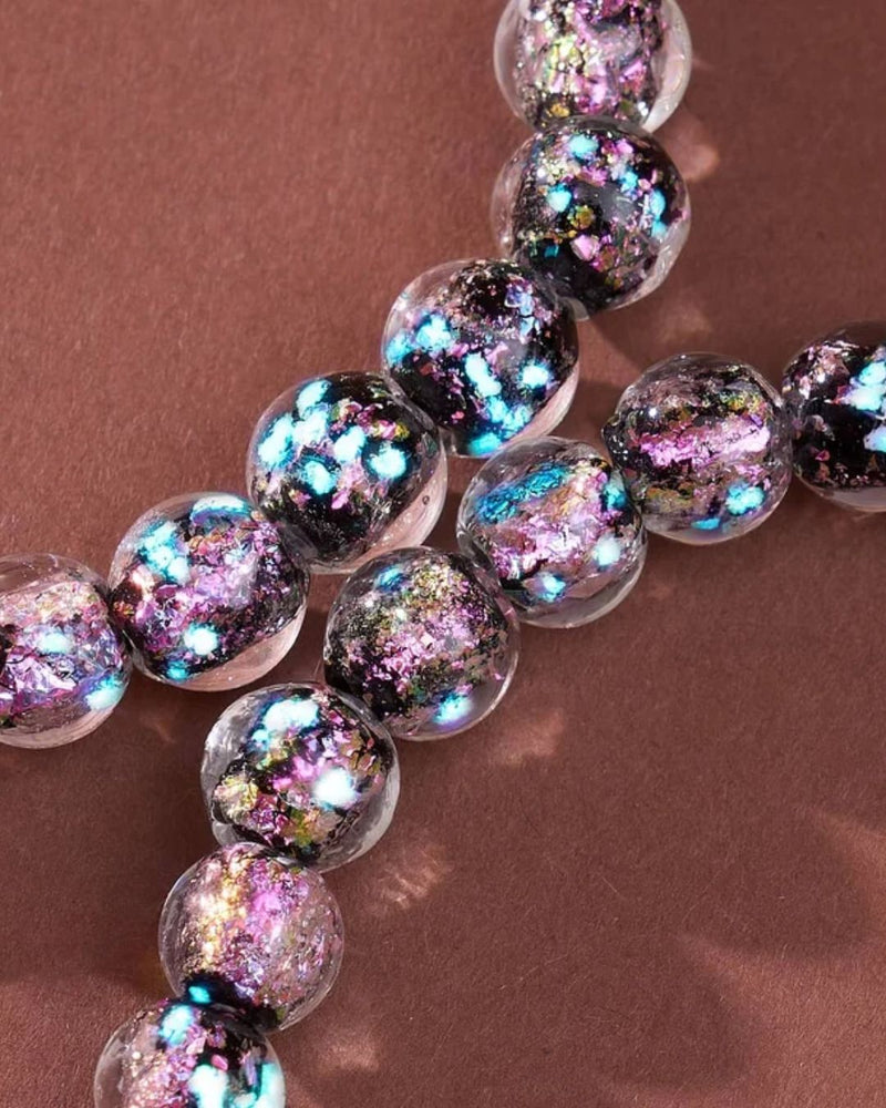 NOGU clear glass bead bracelet with iridescent pink, turquoise, and gold foil flecks in a colorful cosmic style.