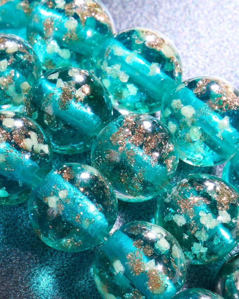 Close-up of glossy turquoise resin beads with shimmering gold flecks and pale floral-like inclusions.