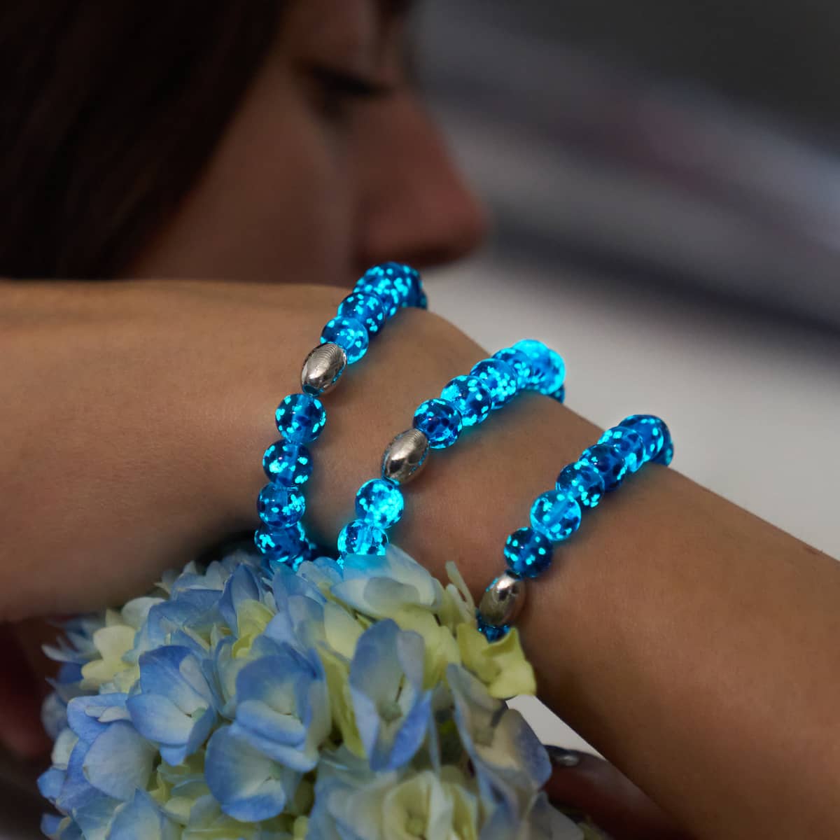 Topaz Flame Firefly Glass stretch bracelets with blue glowing beads and .925 sterling silver accents on wrist by NOGU