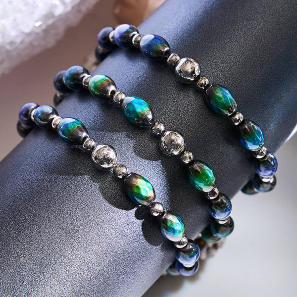 Chromata Mood Stone Fabergé Bracelets with oval color-changing beads and silver spacer beads displayed on black stand by NOGU.