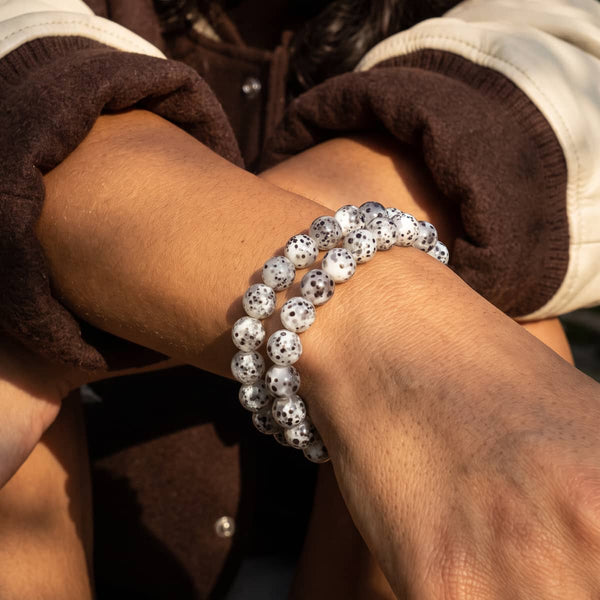 Casa Blanca stretch bracelet with white terrazzo glass beads flecked in black, worn layered on the wrist.