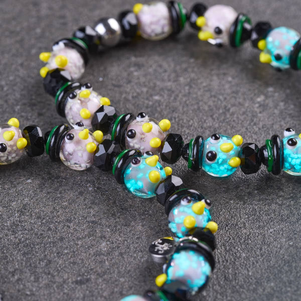 Doctor Nightshade Firefly Glass owl bracelet with turquoise and lavender owl beads, yellow details, black faceted beads and green spacers.
