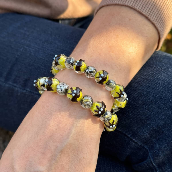 Midnight Flight firework glass bat bracelet with yellow beads, dark bat details, and silver-toned accents on clear elastic.