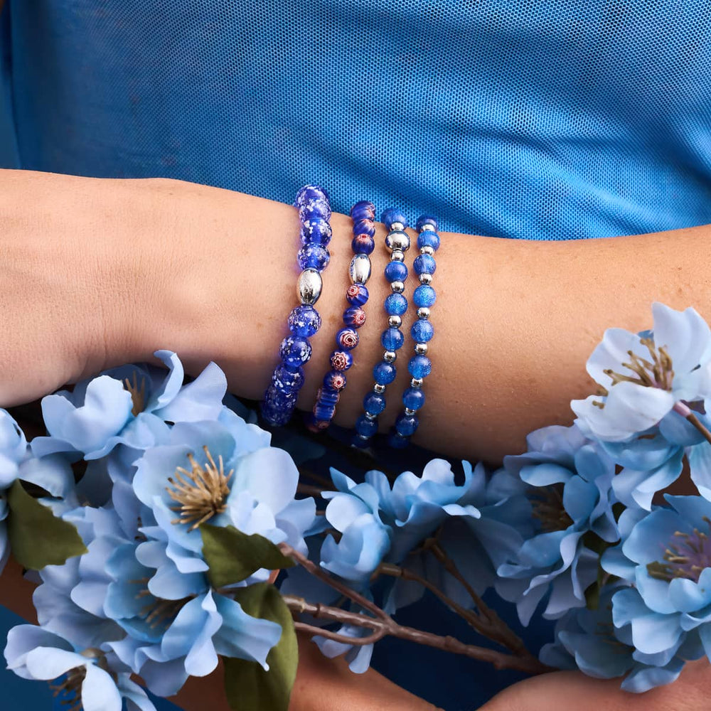 Lapis Lazuli Firefly Glass Bracelet with glowing blue beads and .925 sterling silver clasp worn with other beaded bracelets by NOGU