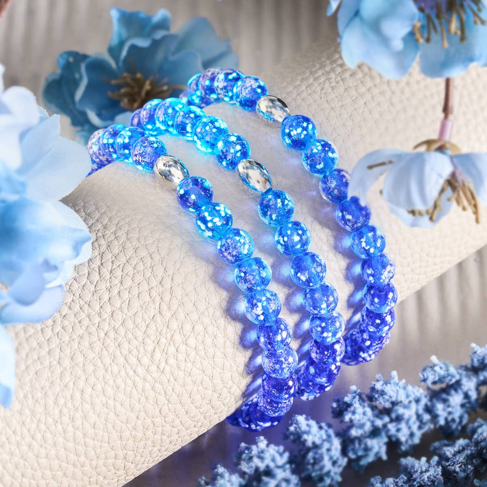 Lapis Lazuli Firefly Glass Bracelets with glowing blue beads and .925 sterling silver accents displayed on textured cushion by NOGU