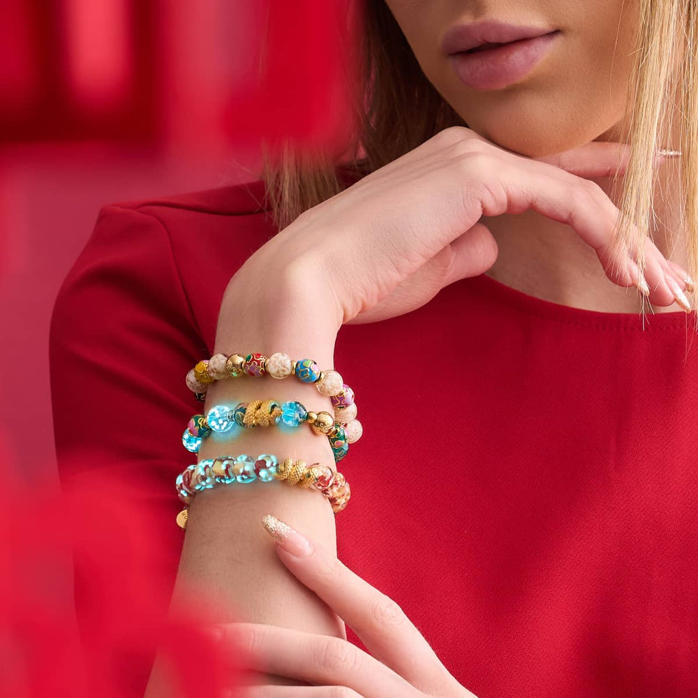 Sea Dragon teal firefly glass and enamel lotus bracelet with 18k gold serpent charm stacked on wrist by NOGU