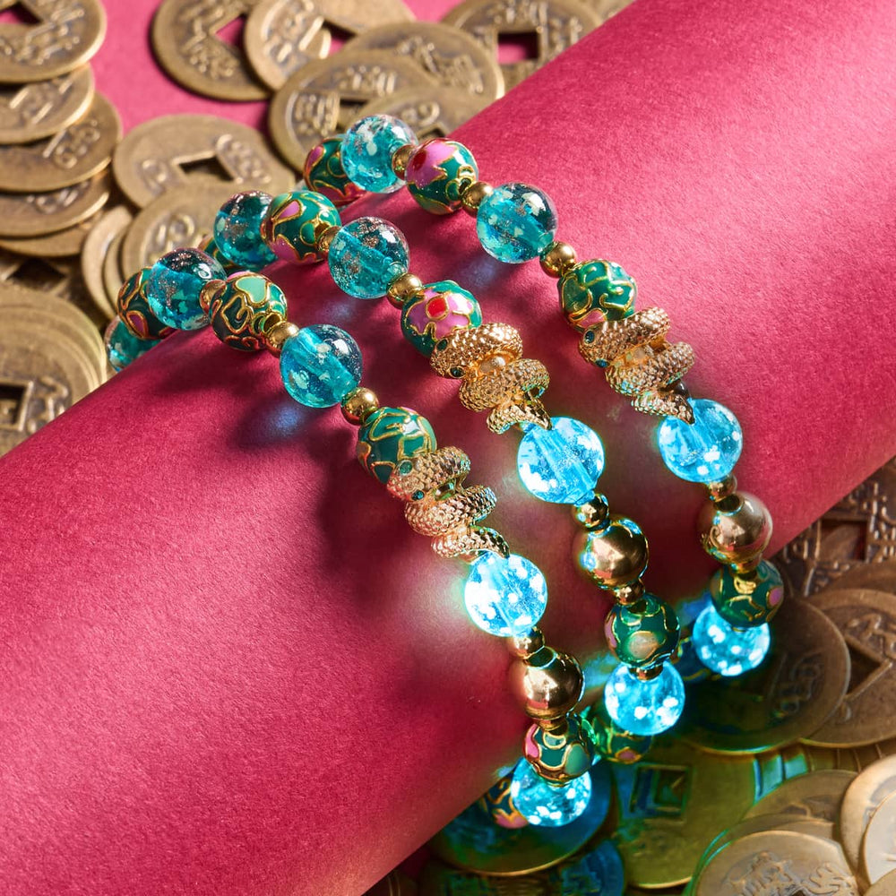 Sea Dragon bracelet with teal firefly glass and enamel lotus beads, gold serpent charm, and stainless steel on red with Chinese coins by NOGU